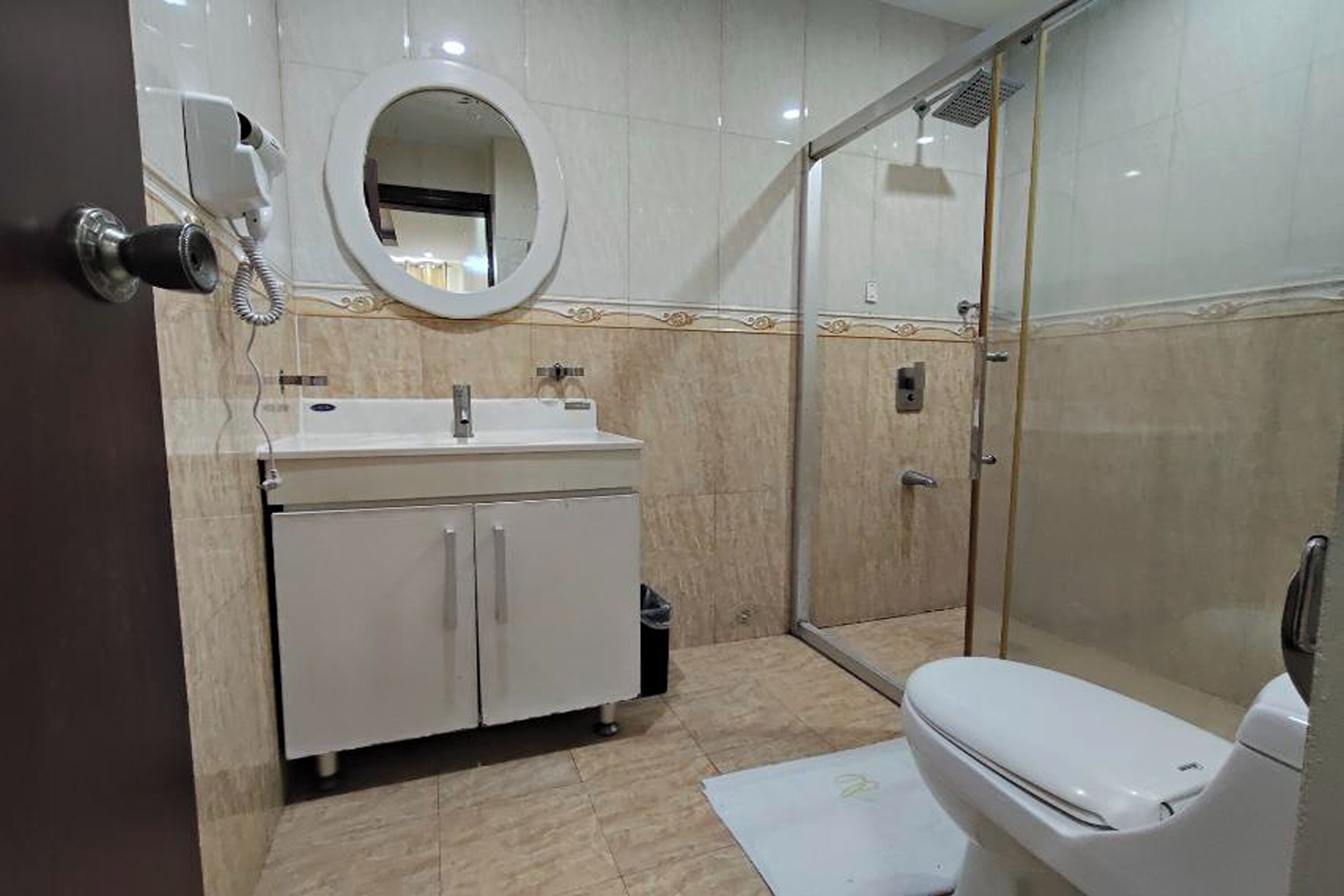 Un bany modern amb dutxa envidrada en vidre, un lavabo blanc amb mirall i un vàter.