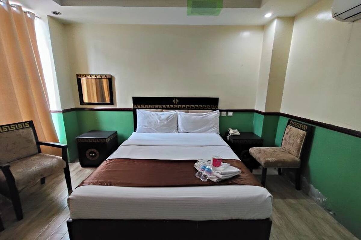 A hotel room with a bed, two nightstands, a chair, and a small table.