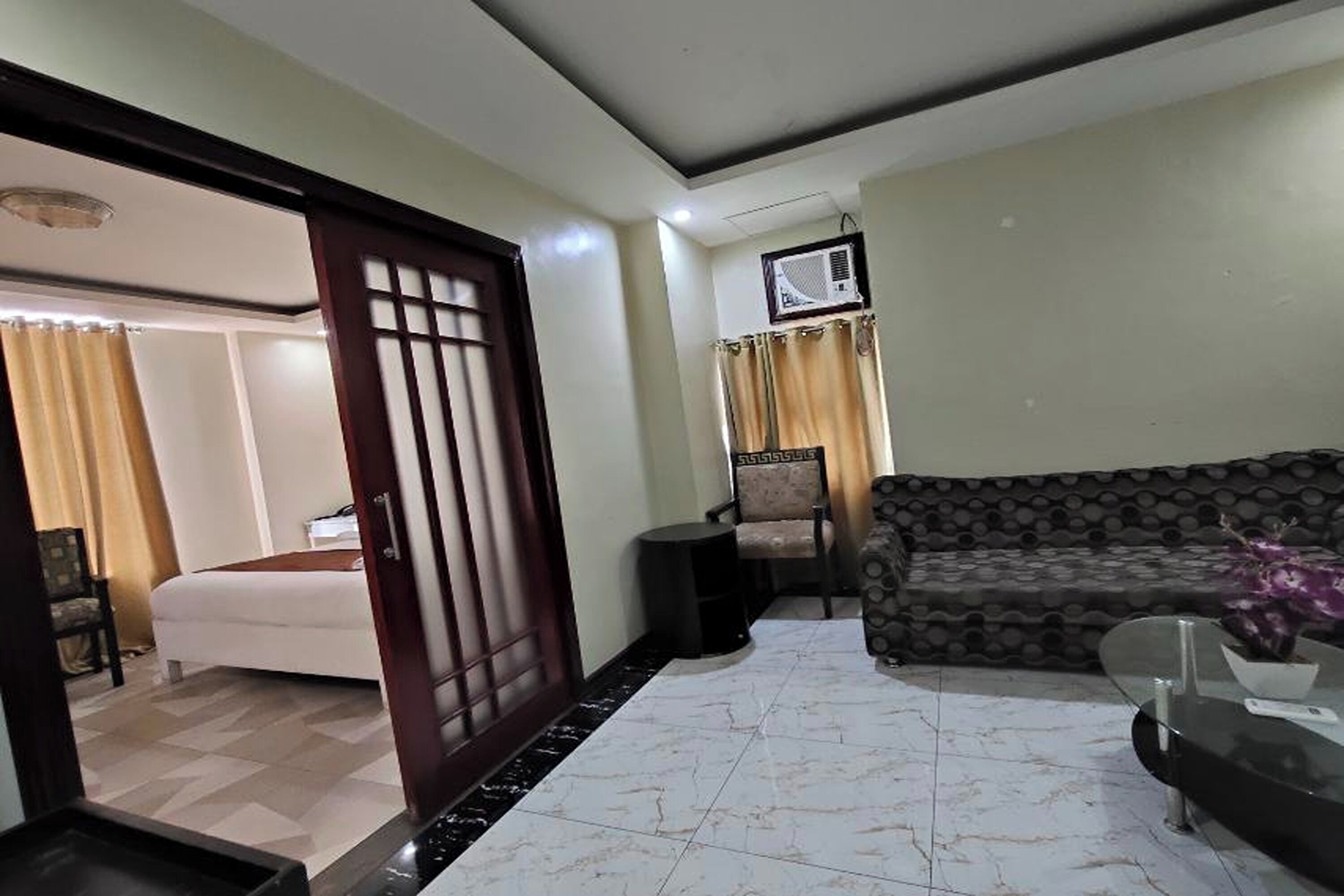 A hotel room with a bed, a sofa, a small table, and a TV.