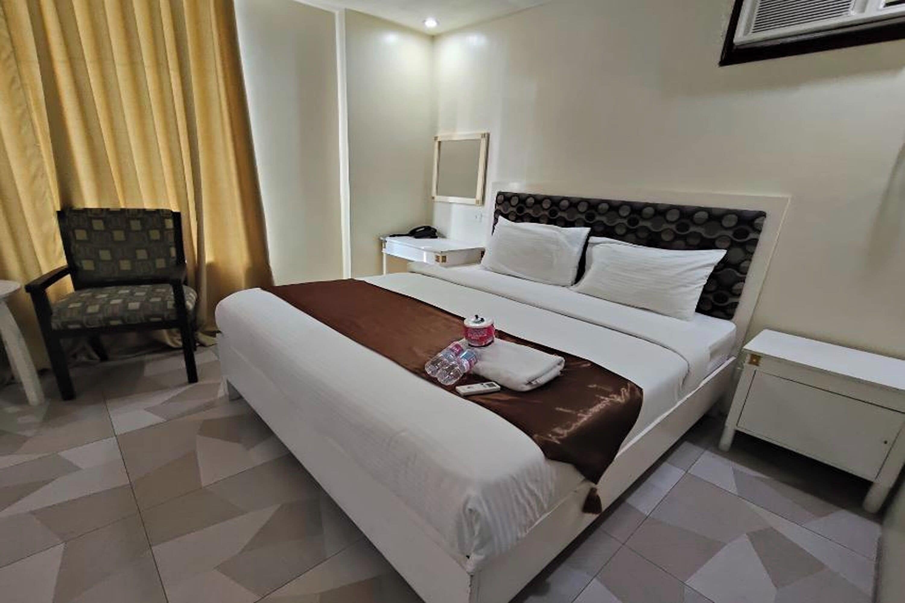 Une chambre d’hôtel avec un grand lit, une chaise, une table de chevet et une petite table.