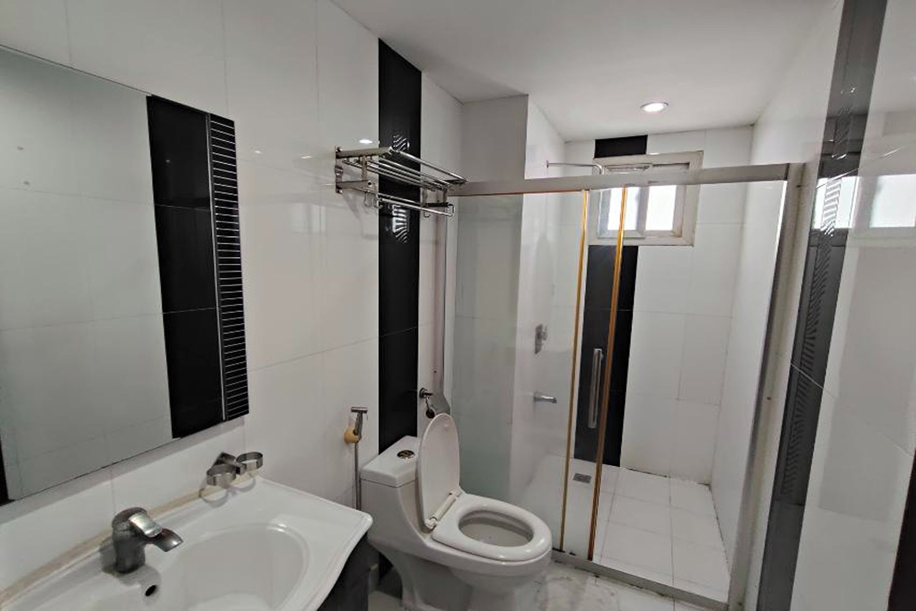 A modern bathroom with a glass-enclosed shower, a white sink, and a toilet.