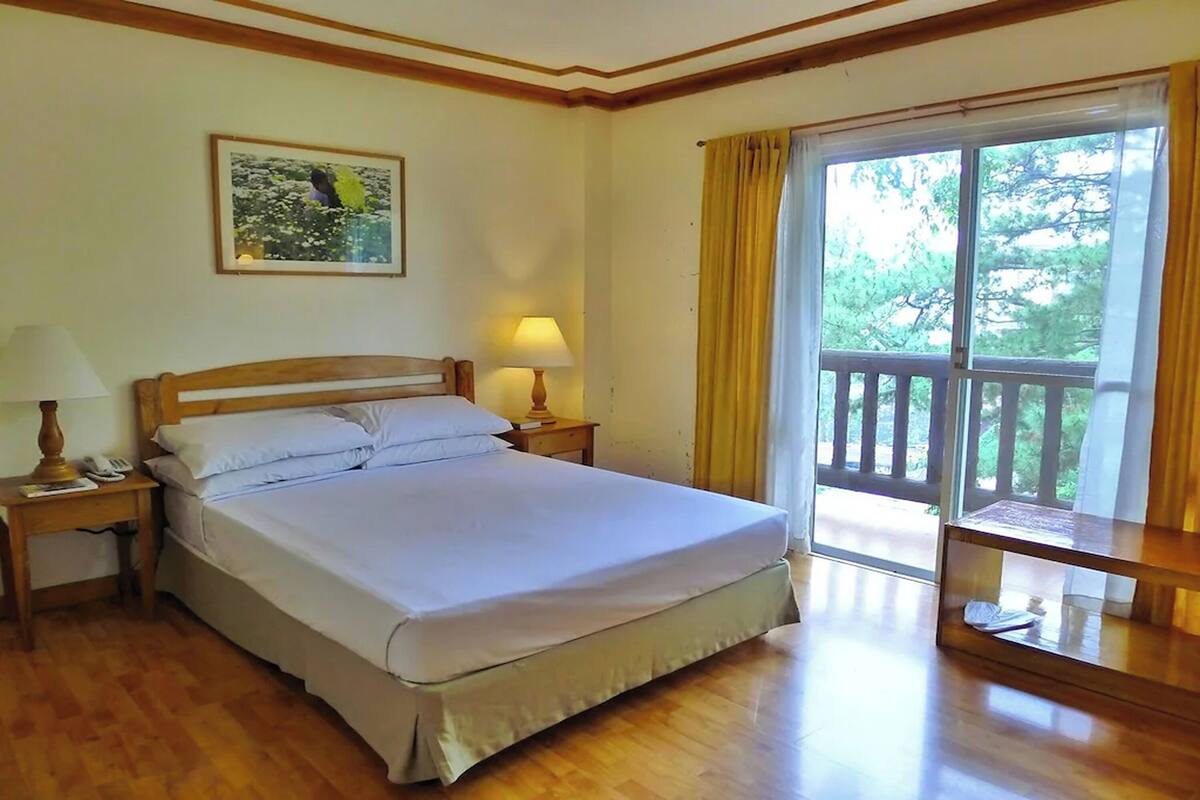 A neatly made bed with white linens, a bedside lamp, and a framed picture on the wall.