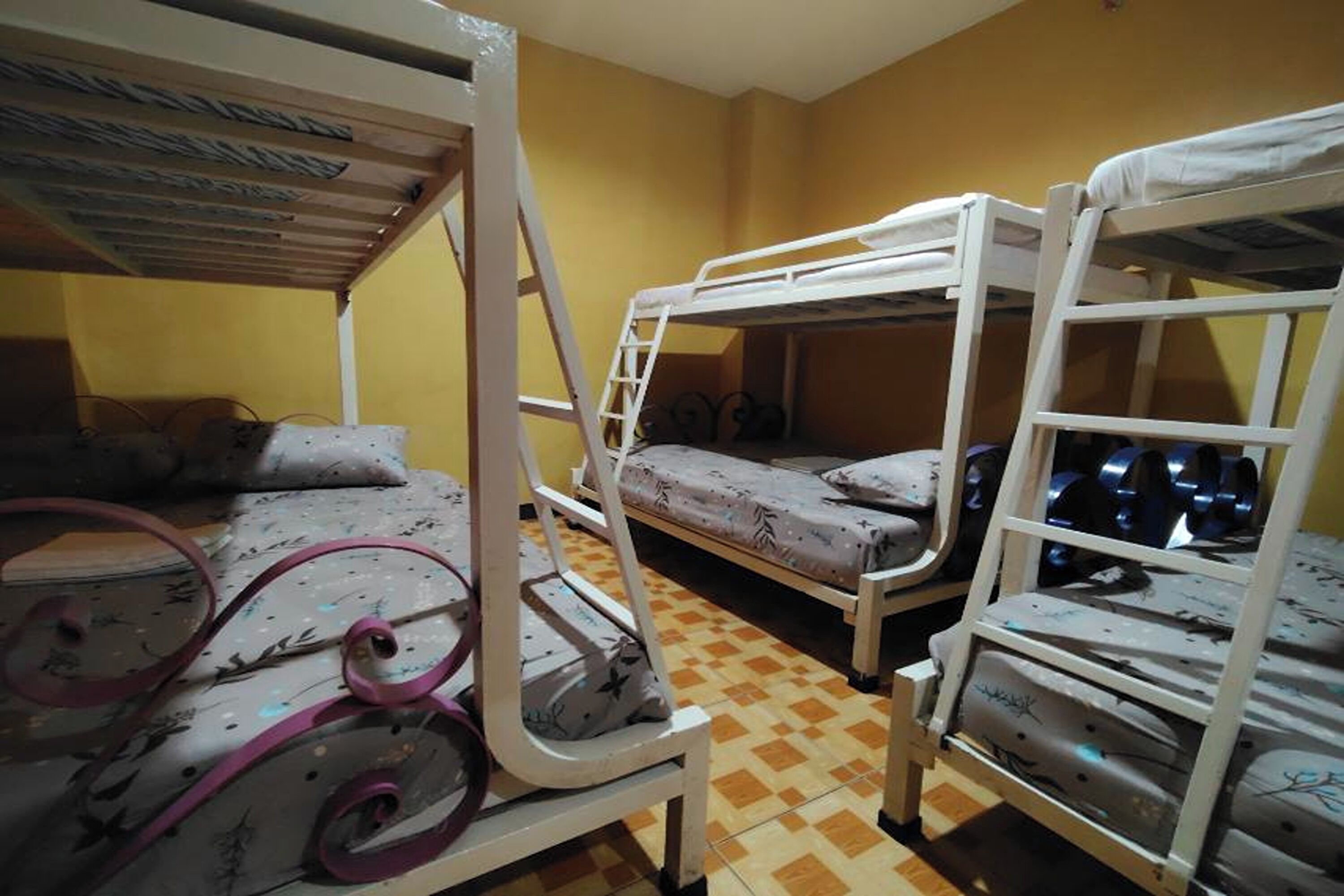 A room with bunk beds, a ladder, and a patterned bedspread.