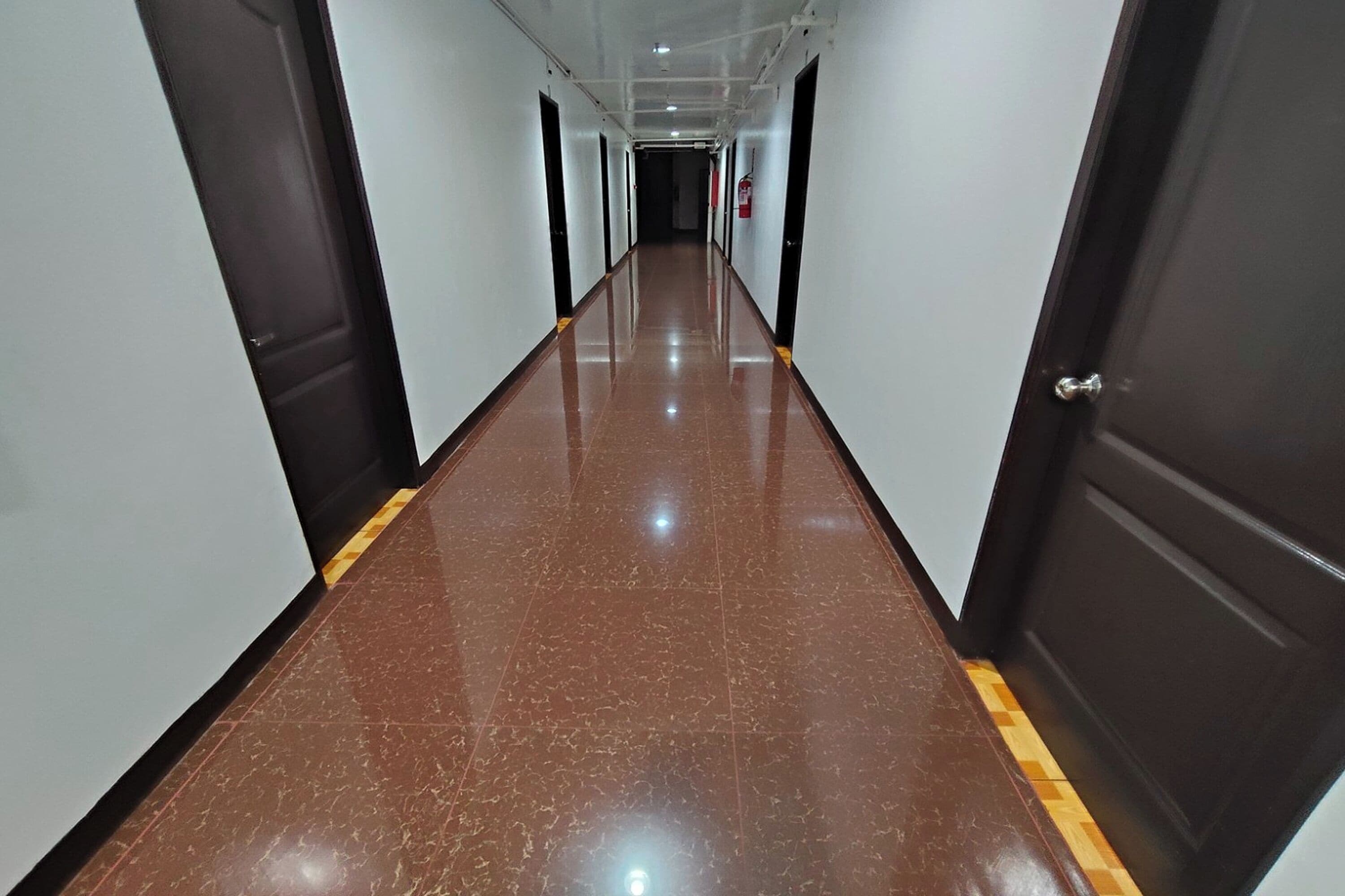 Un pasillo largo y estrecho con suelo brillante y paredes blancas.