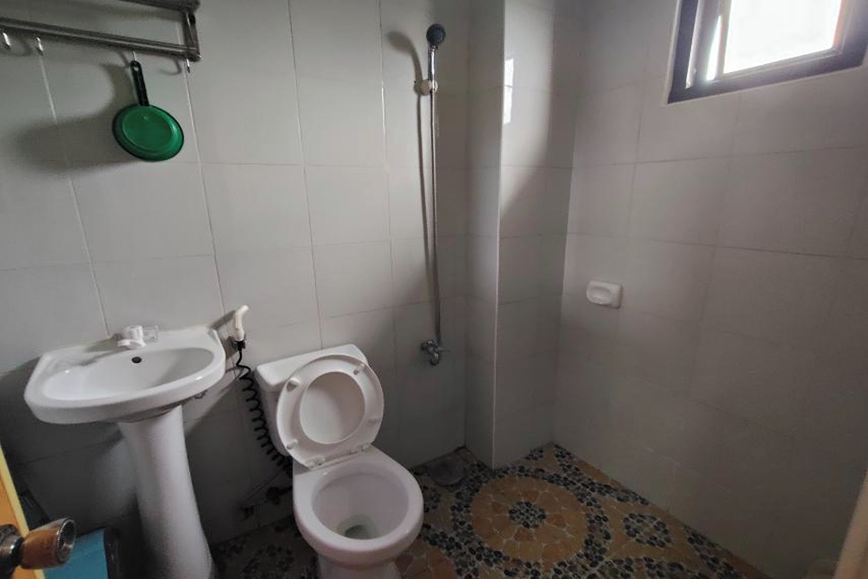 A small bathroom with a toilet, sink, and shower.