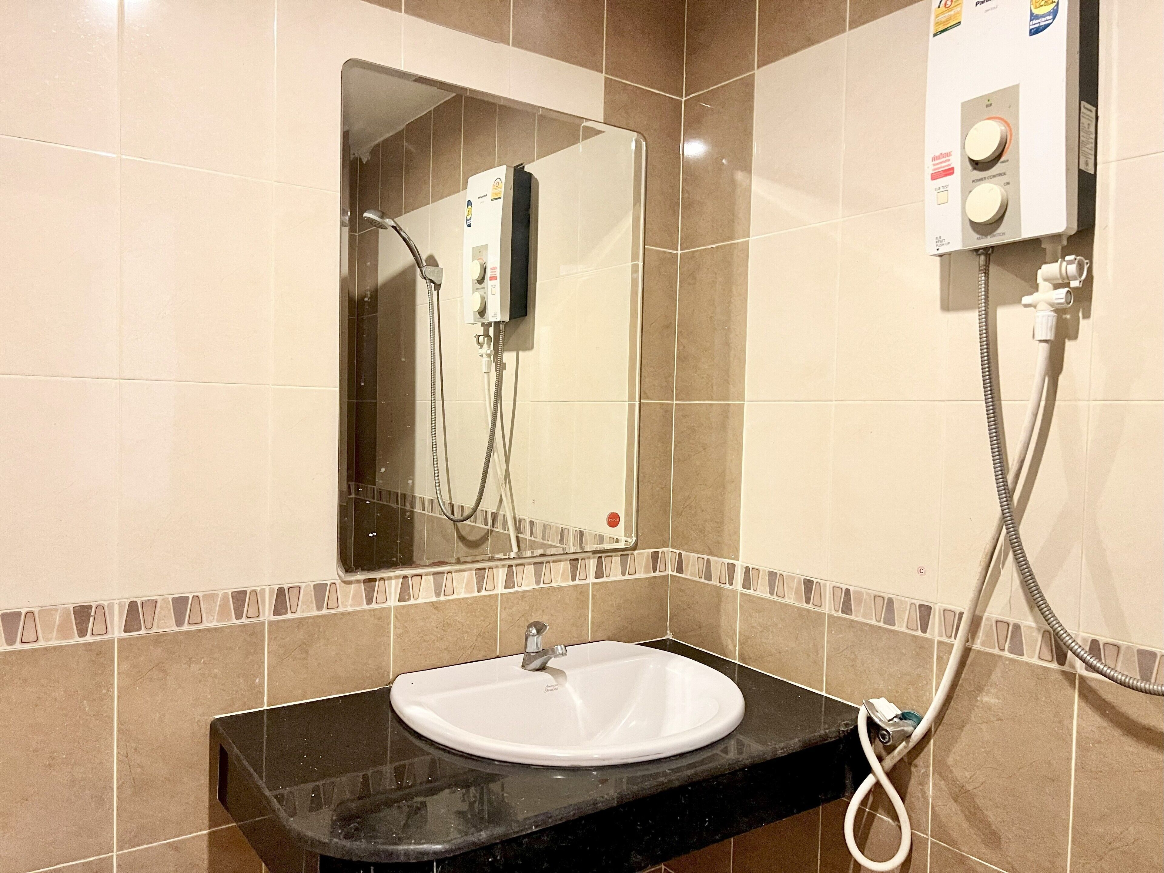 A bathroom with a white sink, a mirror, and a shower control panel.