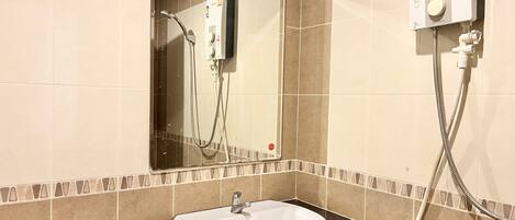 A bathroom with a white sink, a mirror, and a shower control panel.