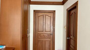 A hallway with a wooden door, a trash bin, and a wooden cabinet.