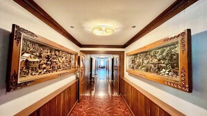 Un pasillo con suelo de mármol, paneles de madera y ornamentada obra de arte en la pared.