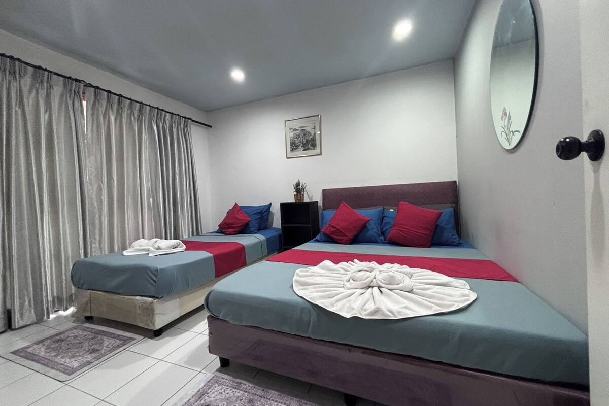 A hotel room with two beds, a large mirror, and a small table with a plant.