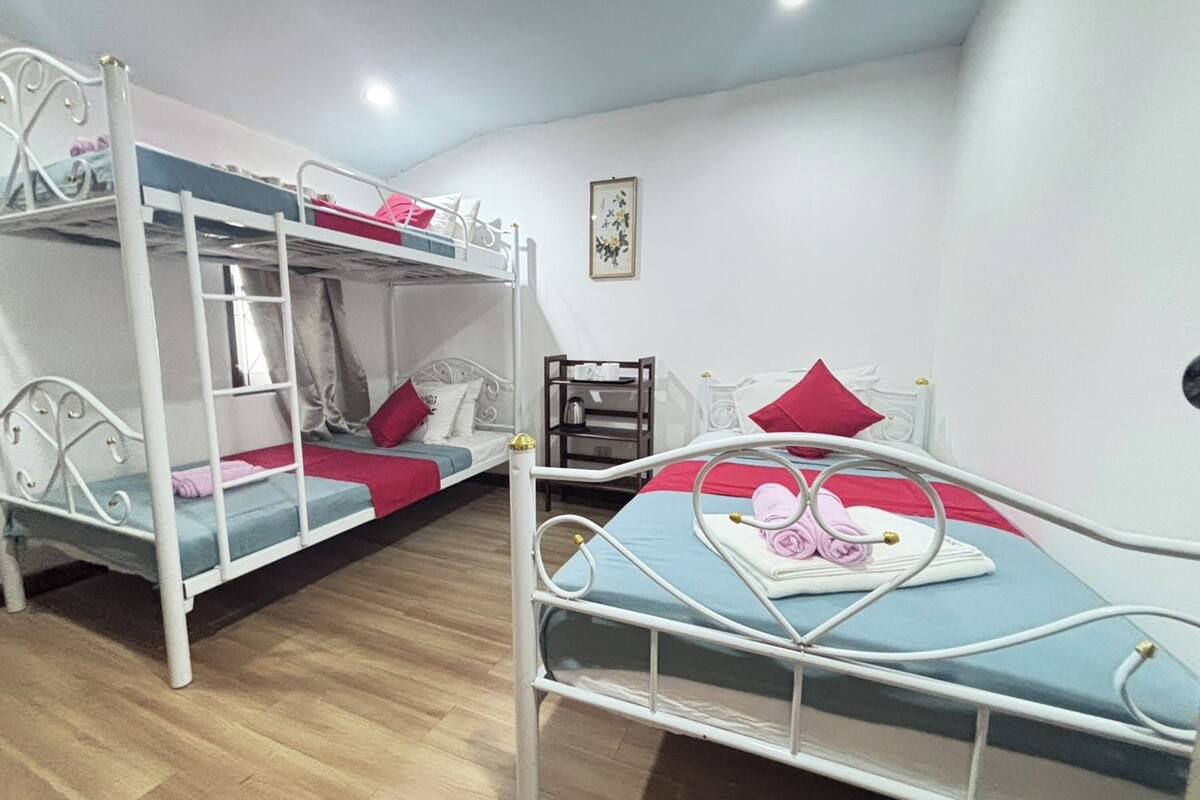 A room with bunk beds, a small desk, and a framed picture on the wall.