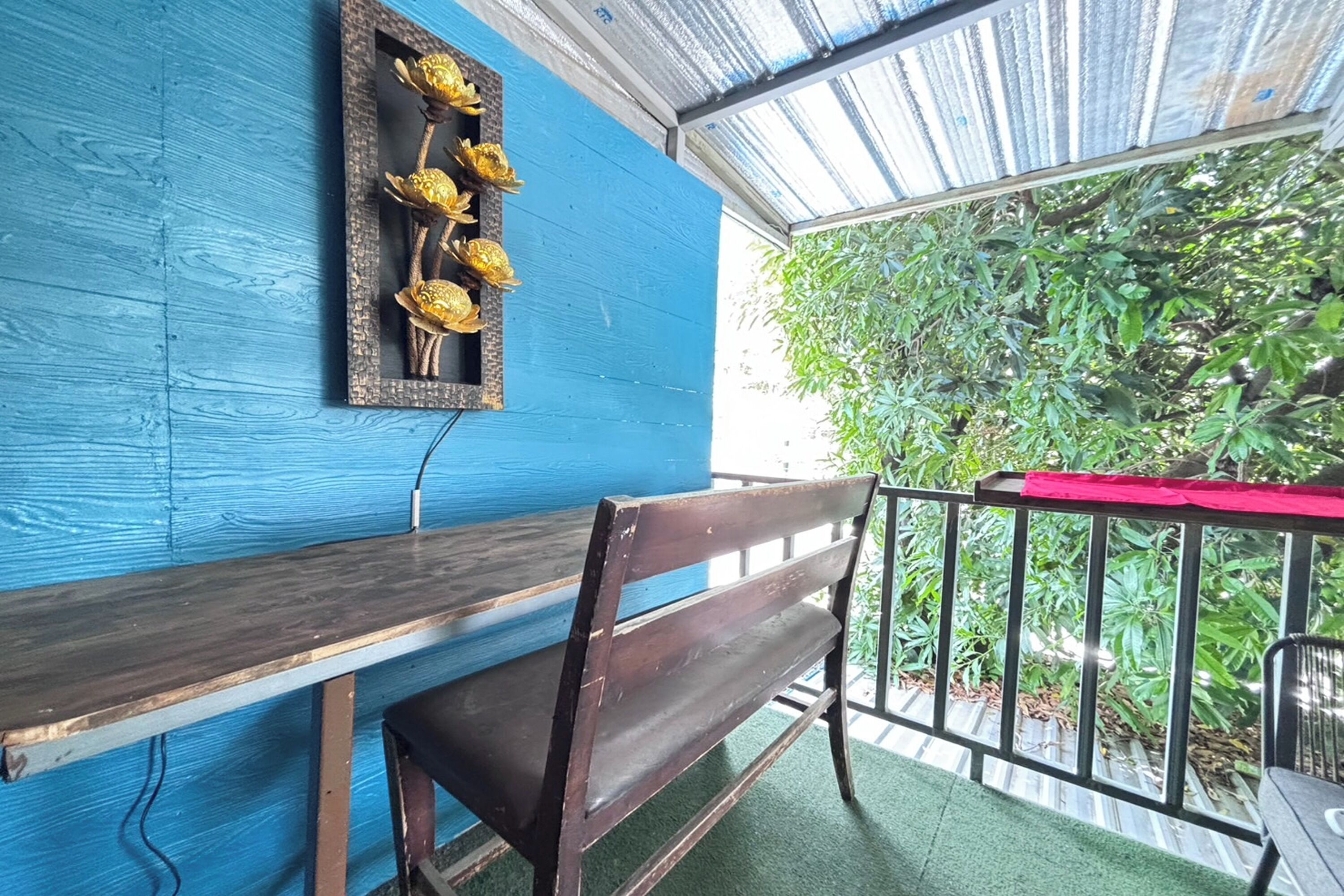 A blue wall with a wooden bench and a framed picture of golden flowers.