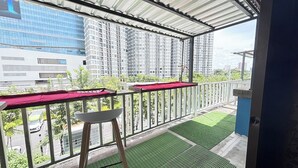 A balcony with a view of high-rise buildings, a white chair, and a red tablecloth. - Sunshiny-BB Hostel near Punnavithi BTS station (Bangkok)