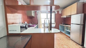 A compact kitchen with a refrigerator, microwave, and a small sink. - Sunshiny-BB Hostel near Punnavithi BTS station (Bangkok)