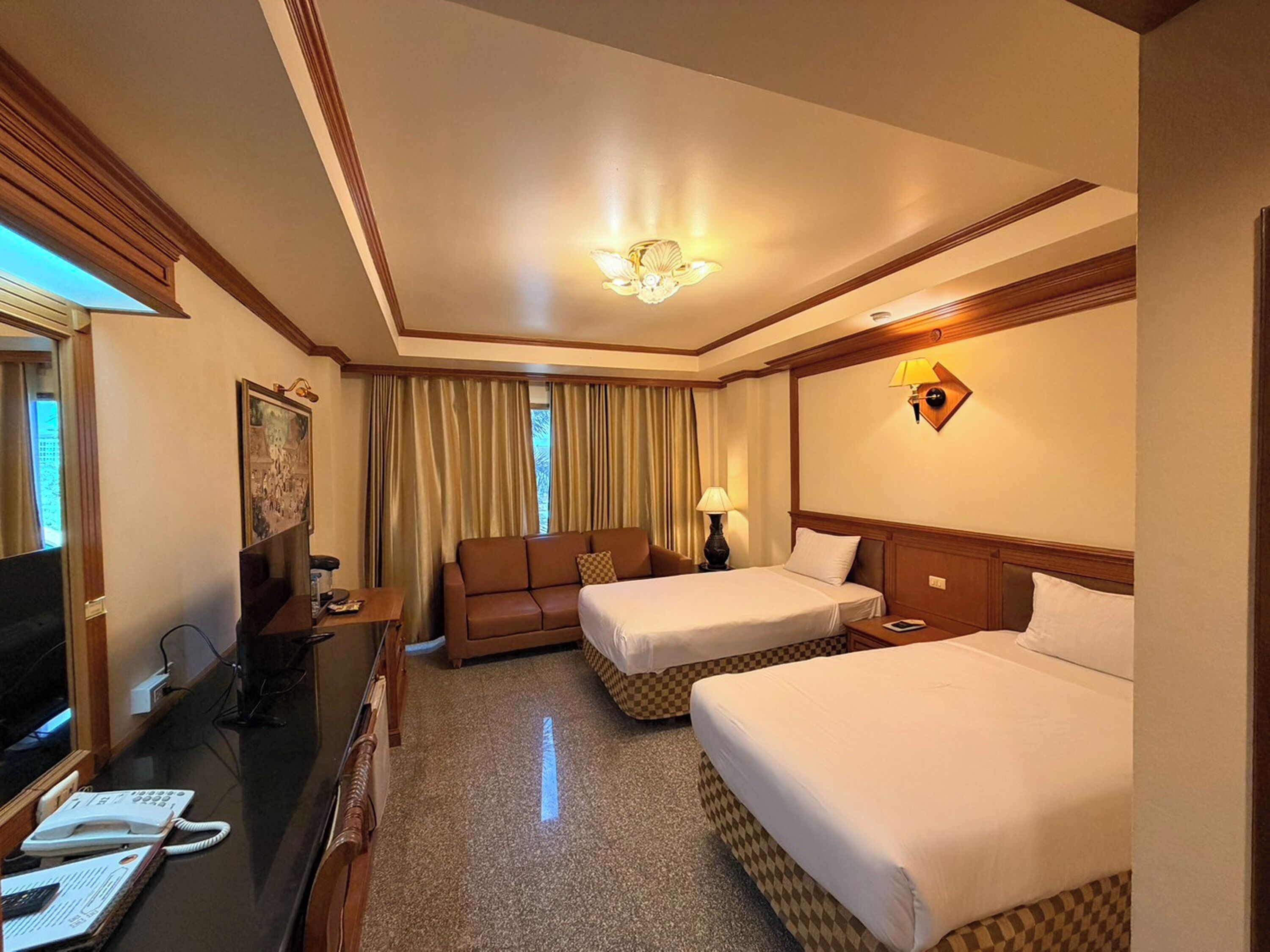A hotel room with two beds, a desk, a chair, a television, and a window with curtains.