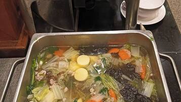 A buffet with various dishes including a soup with vegetables and meat, a stir-fry, and other prepared foods.
