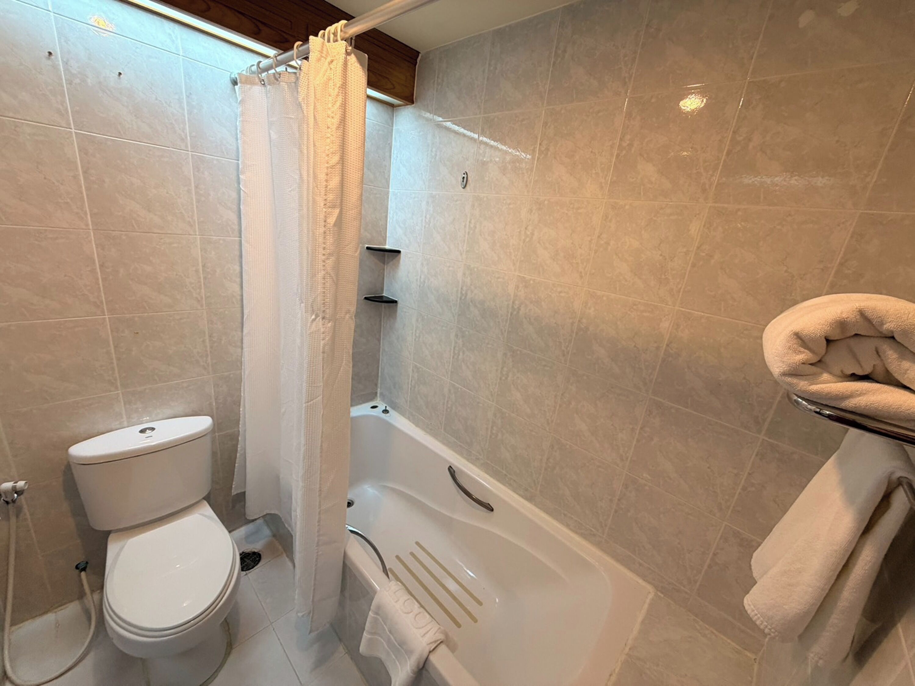 Un baño con inodoro, ducha con cortina y bañera.