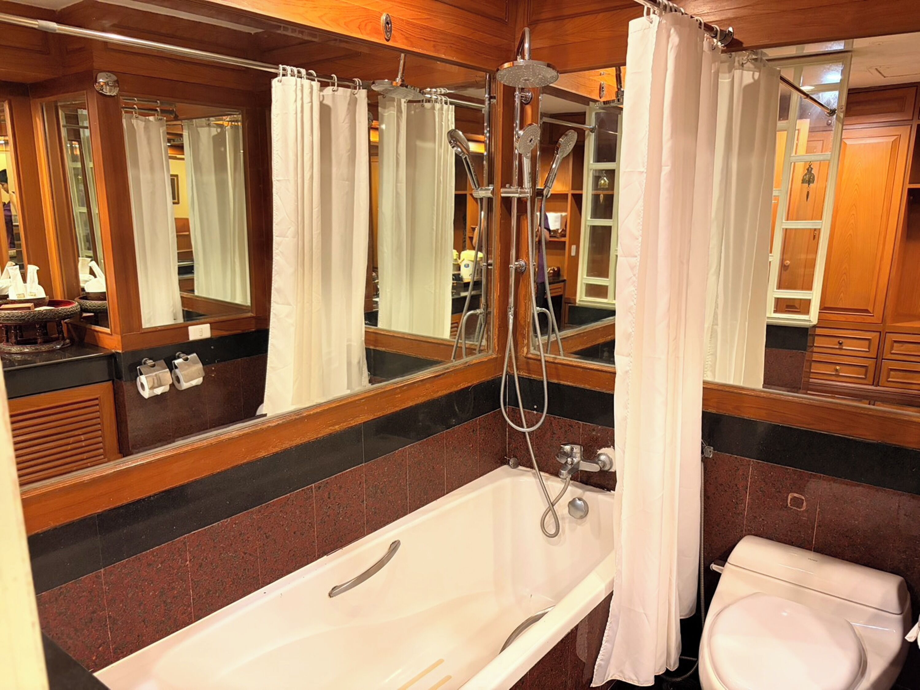 Un baño con bañera, inodoro, ducha y un espejo grande.