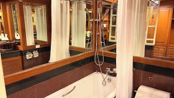 Un baño con bañera, inodoro, ducha y un espejo grande.
