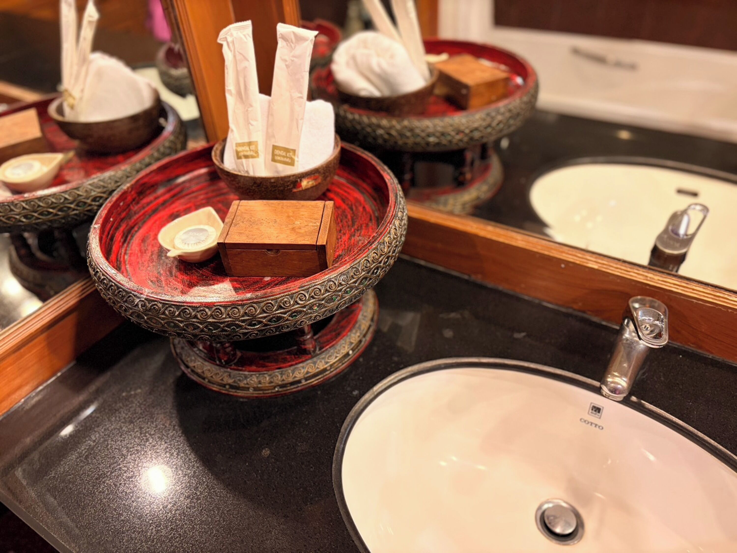 Une salle de bain équipée d’un lavabo, d’un miroir et de jolis récipients décoratifs contenant des mouchoirs et une boîte.