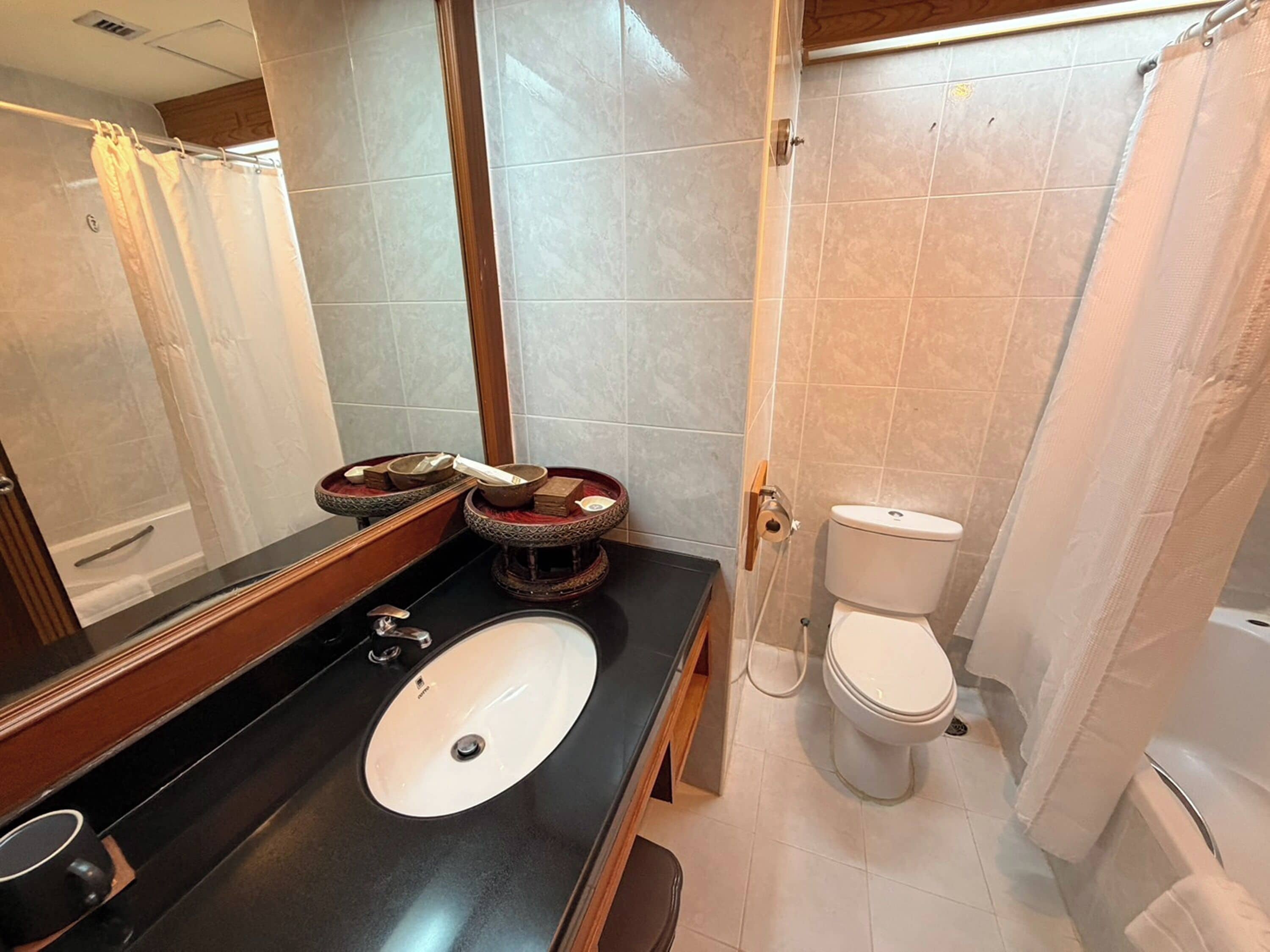 A bathroom with a sink, mirror, toilet, and shower curtain.