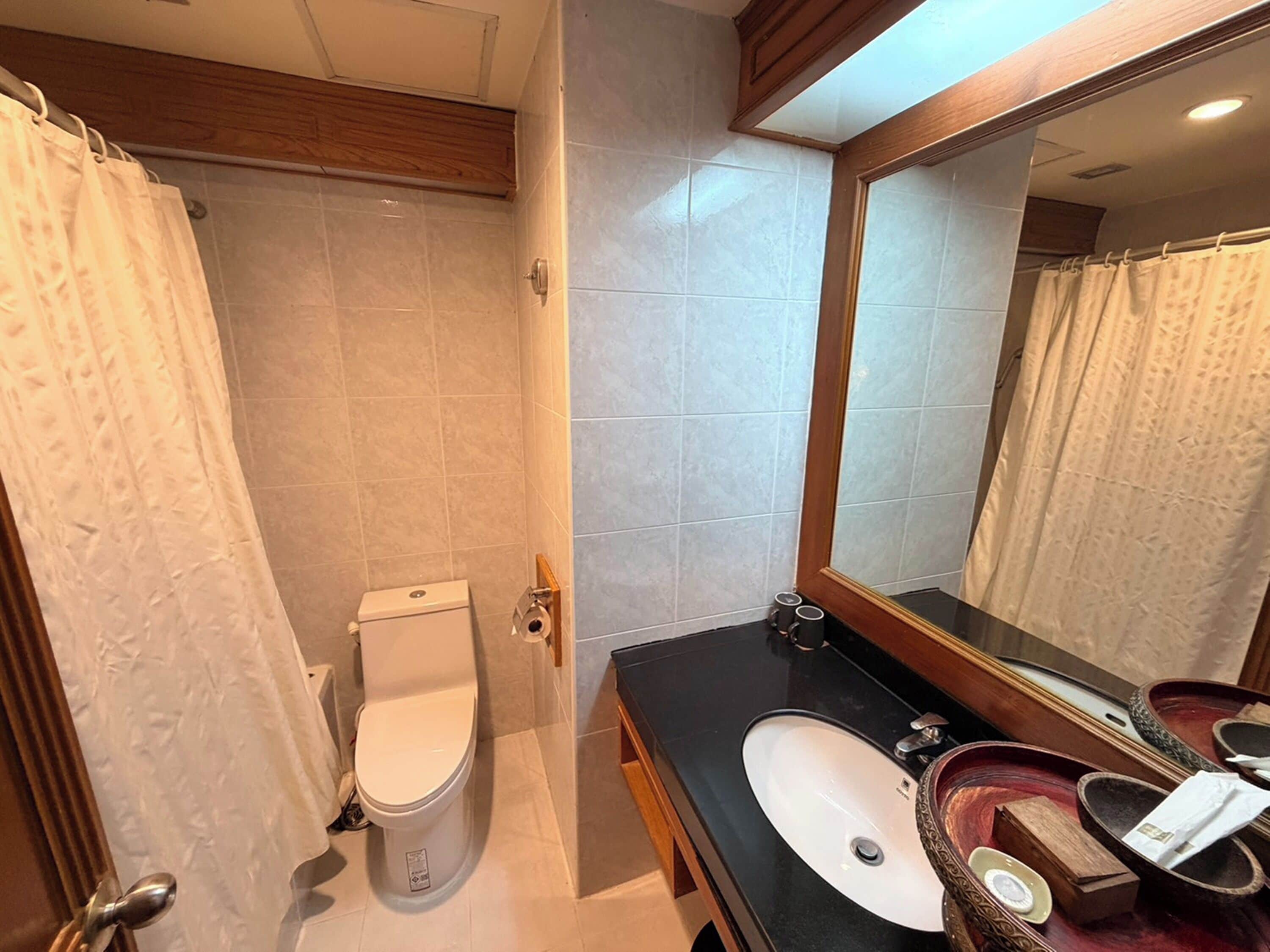 A bathroom with a toilet, sink, mirror, and shower curtain.