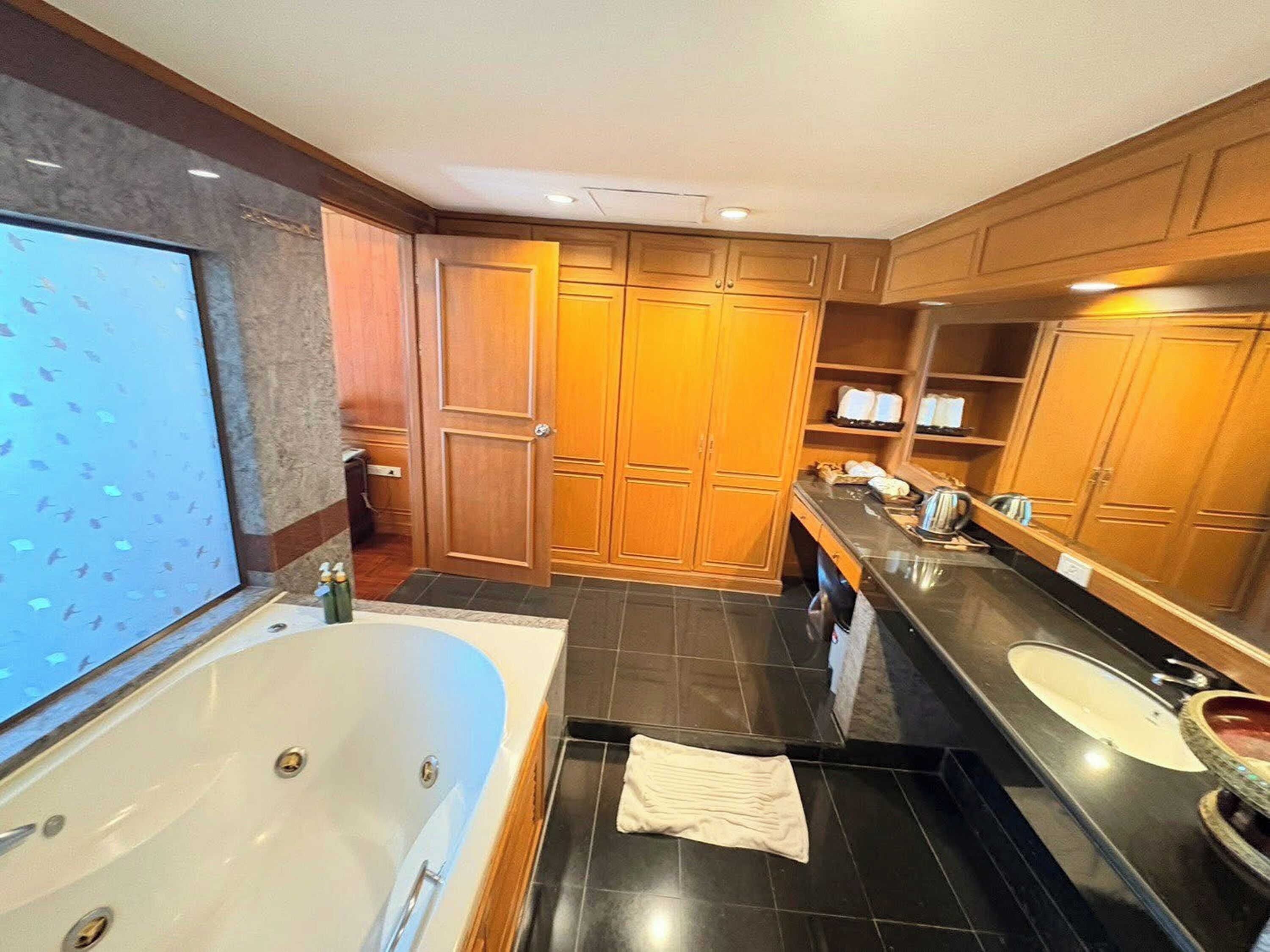 A modern bathroom with a large bathtub, a vanity with a sink, and a mirror.