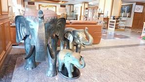 Eine Lobby mit einer großen Elefantenskulptur, einem braunen Sofa und einem Empfangstresen.