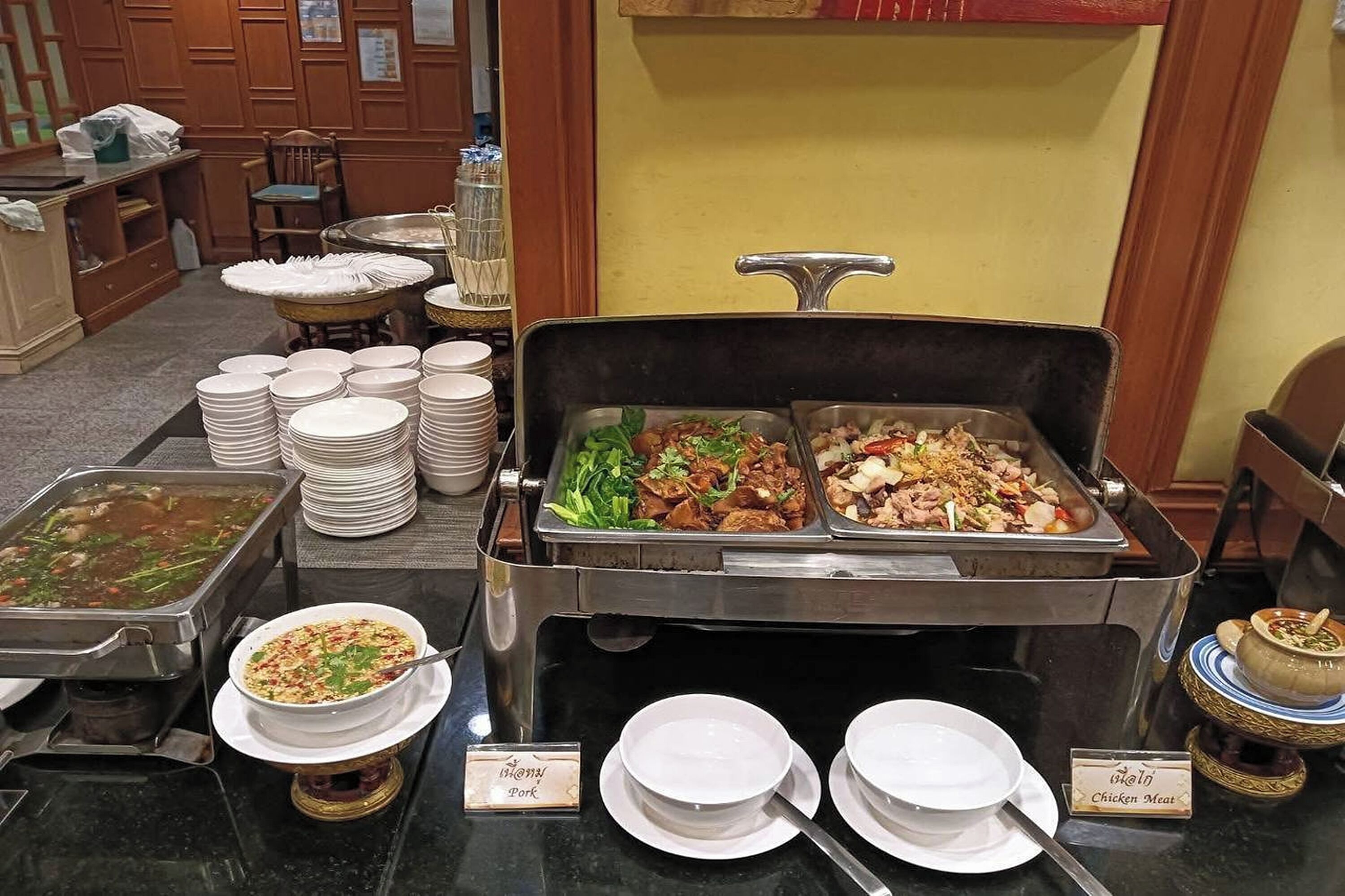 A buffet setup with various dishes and labeled serving utensils.