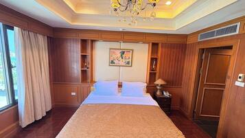 Una habitación de hotel con una cama grande, paneles de madera, un candelabro y un cuadro en la pared.