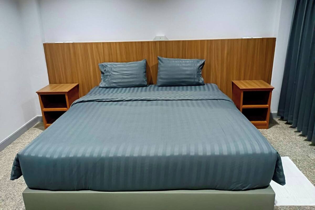 Ein ordentlich bezogenes Bett mit einem Holzkopfteil, zwei Kissen und zwei Nachttischen aus Holz.