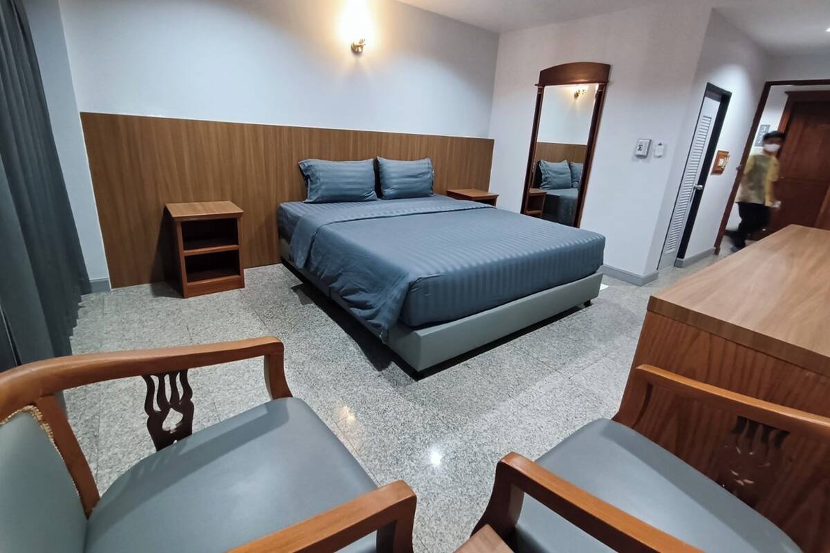 Ein Hotelzimmer mit einem Bett, zwei Nachttischen, einem Spiegel, einem Holztisch und zwei Stühlen.