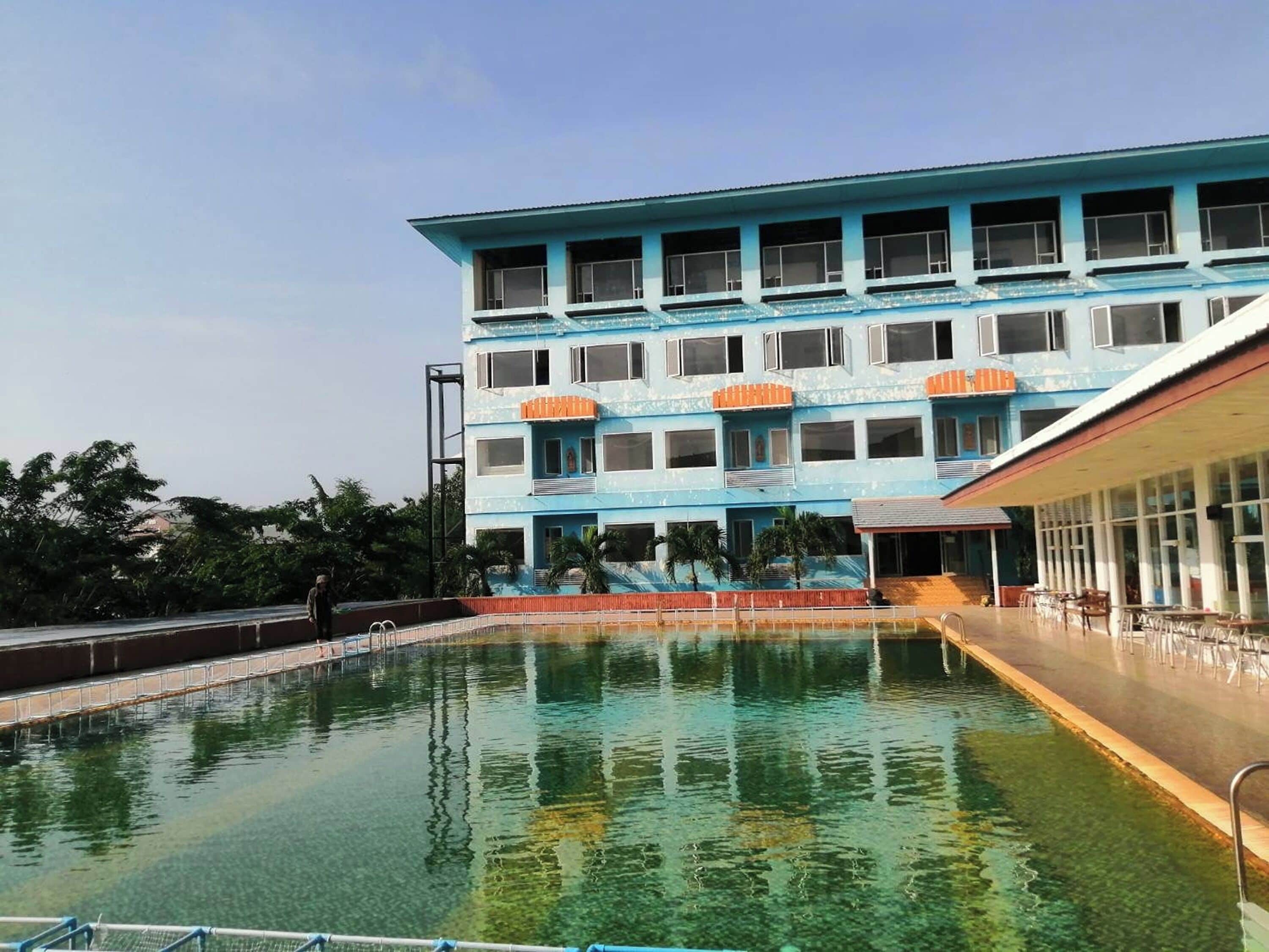 A multi-story building with a pool in front.
