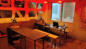 Een kamer met een houten eettafel, een laptop en een raam met zonwering.