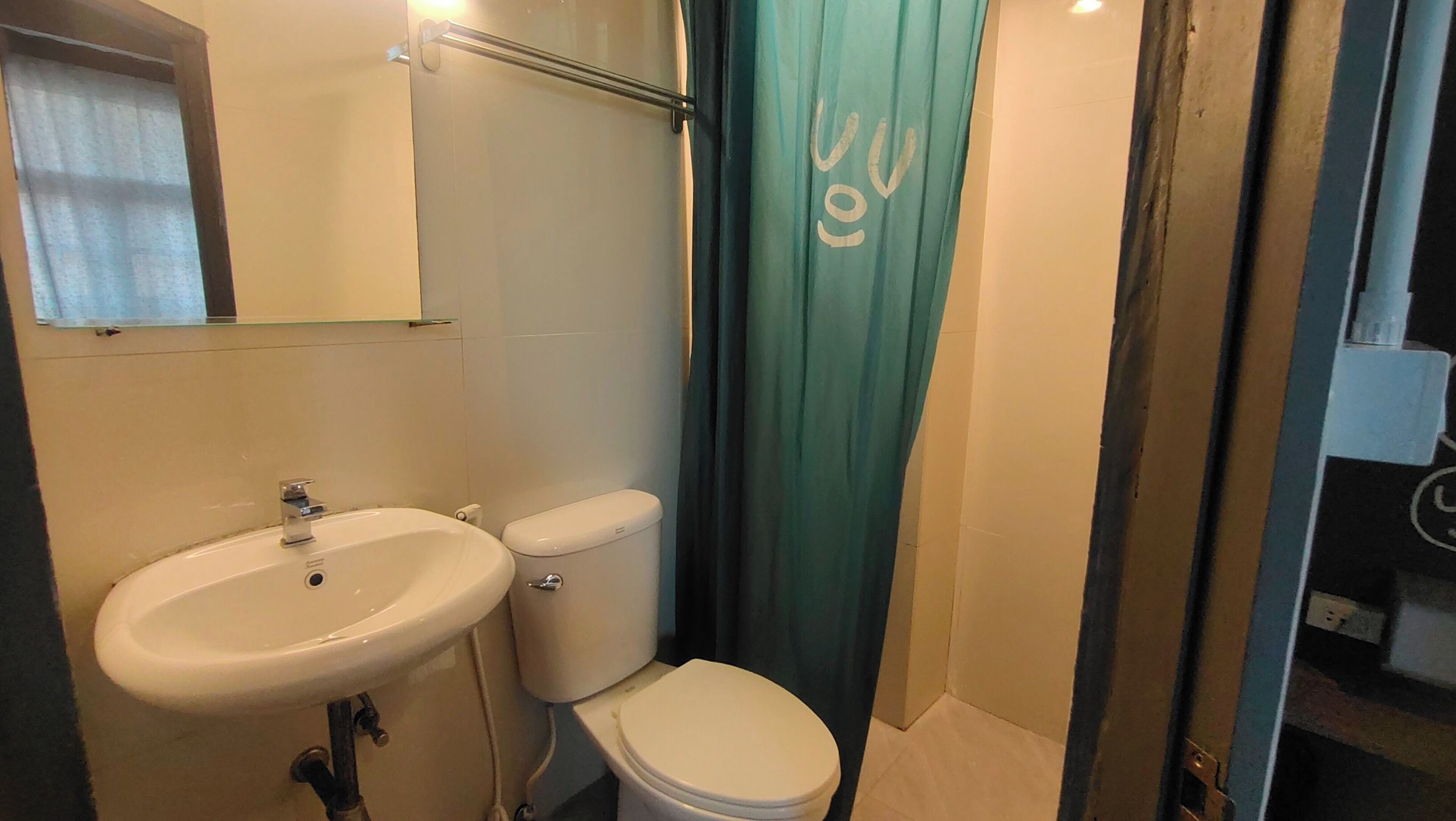 Un baño con lavamanos blanco, inodoro y cortina de ducha.
