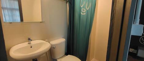 Un baño con lavamanos blanco, inodoro y cortina de ducha.