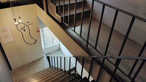 Een trap met metalen leuningen en een handgetekende gloeilamp aan de muur.