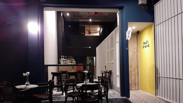 Een restaurantinterieur met tafels en stoelen, een bar en een bord waarop staat 