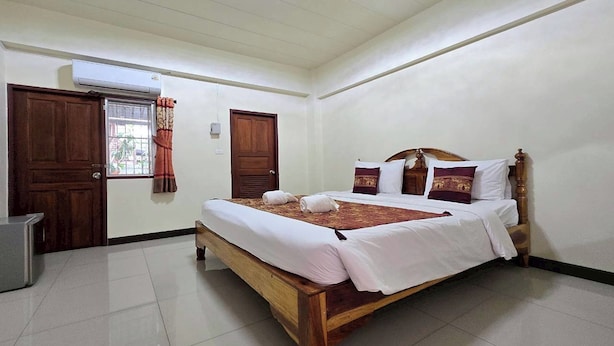 Un dormitorio ordenado con una cama de madera, ropa de cama blanca y una mesita de noche pequeña.