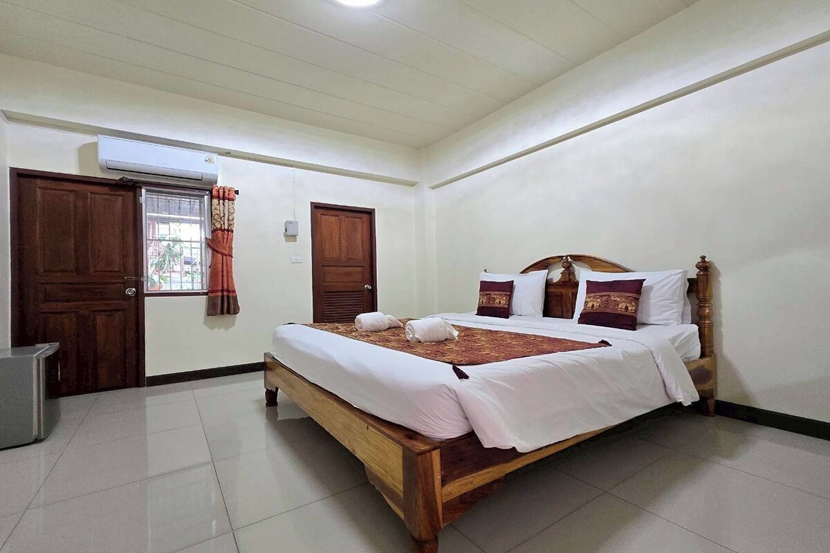 A neatly arranged bedroom with a wooden bed, white bedding, and a small bedside table.