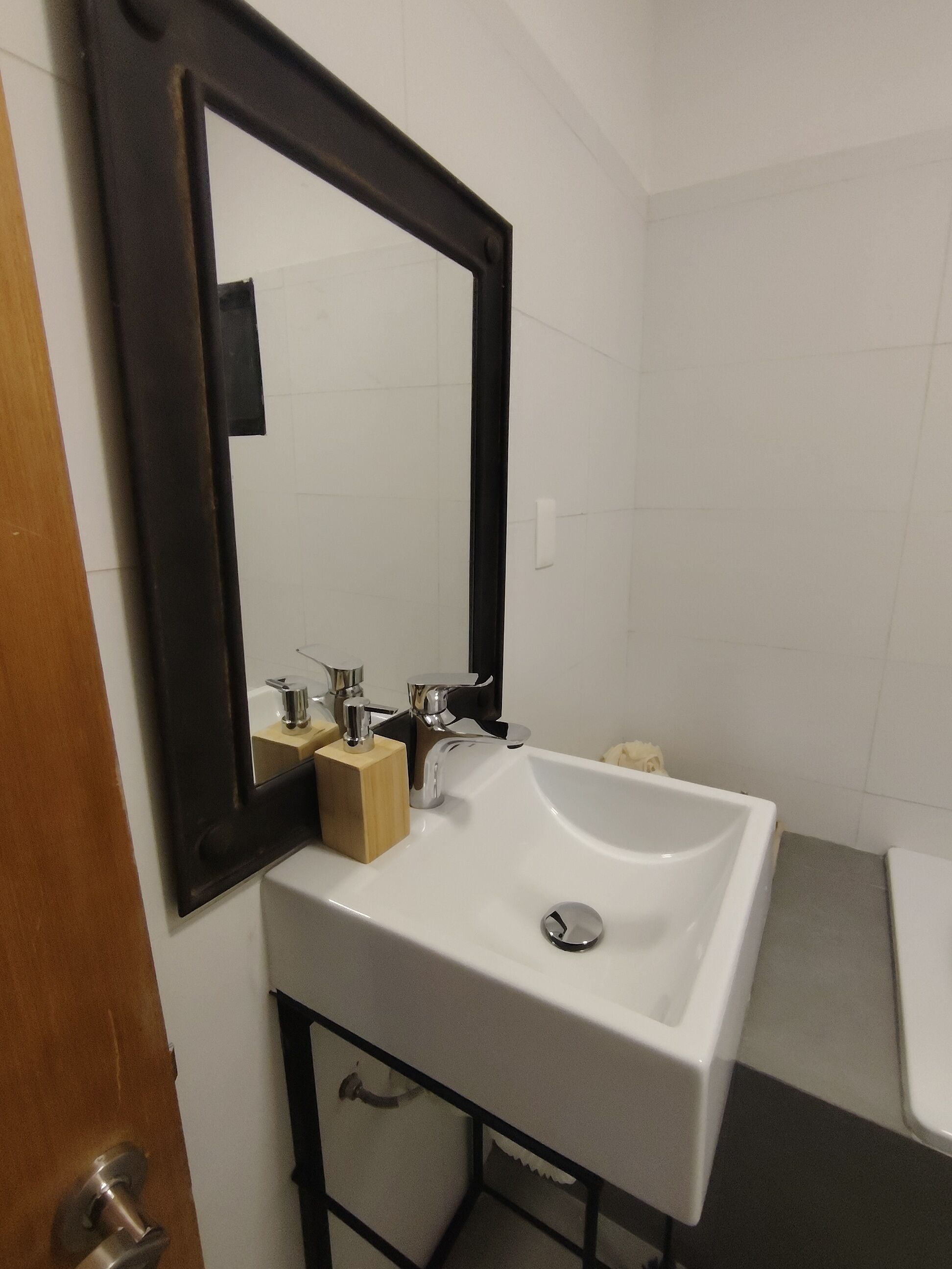 Une salle de bain avec un lavabo blanc, un miroir et des toilettes.