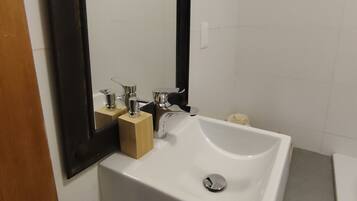 Une salle de bain avec un lavabo blanc, un miroir et des toilettes.