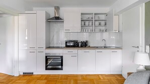 A compact kitchen with white cabinetry, a built-in oven, a microwave, and a coffee maker.