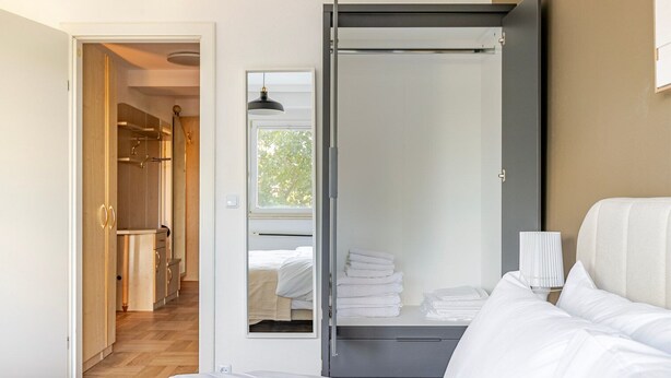 A bedroom with a bed, a bedside lamp, and a view of a bathroom with towels.