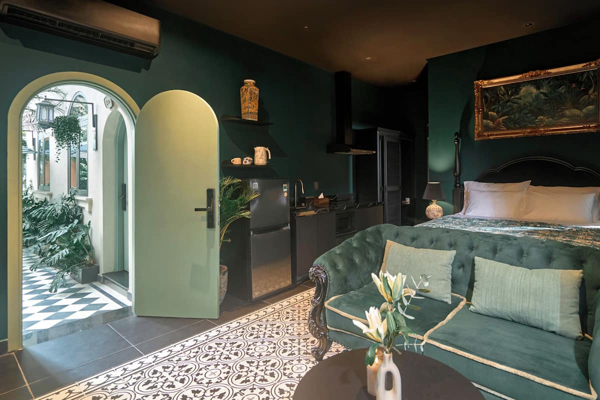 Een slaapkamer met een bed, een bank, een eettafel, een keukenhoek en uitzicht op buiten.