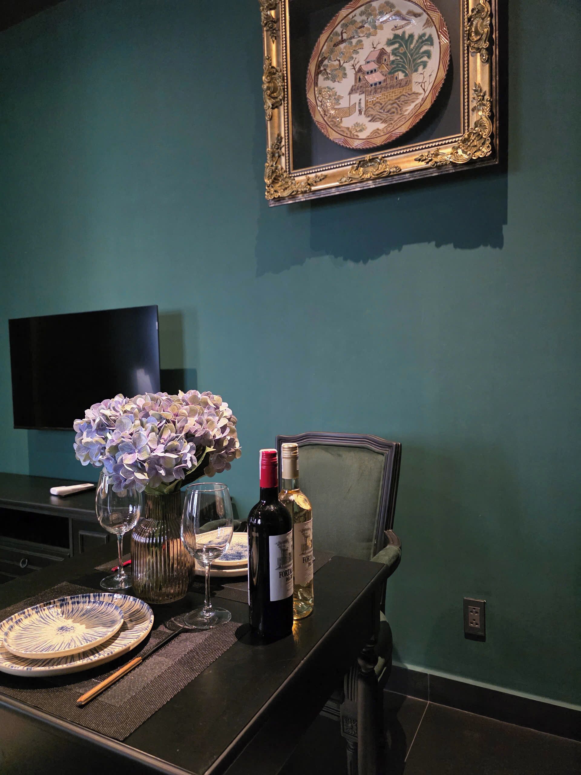 Une table à manger avec des assiettes, des verres à vin et un vase de fleurs.