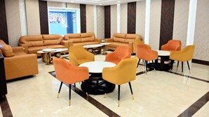 Un área de descanso moderna con sofás de cuero y sillones naranja dispuestos alrededor de una mesa de centro.