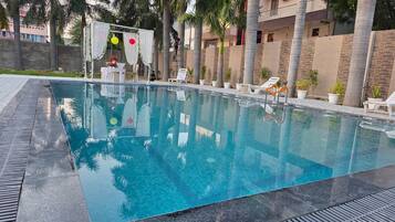 Una piscina con agua cristalina, rodeada de palmeras y sillas de descanso.