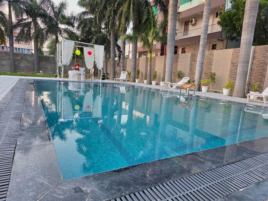 Una piscina con agua cristalina, rodeada de palmeras y sillas de descanso.
