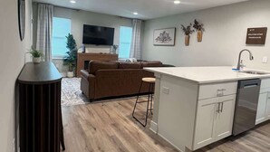 Een moderne keuken met een centraal eiland, een zithoek met een bank en een flatscreen-televisie.